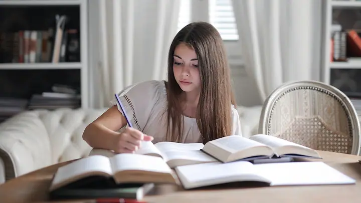 Adolescente estudando com livros abertos